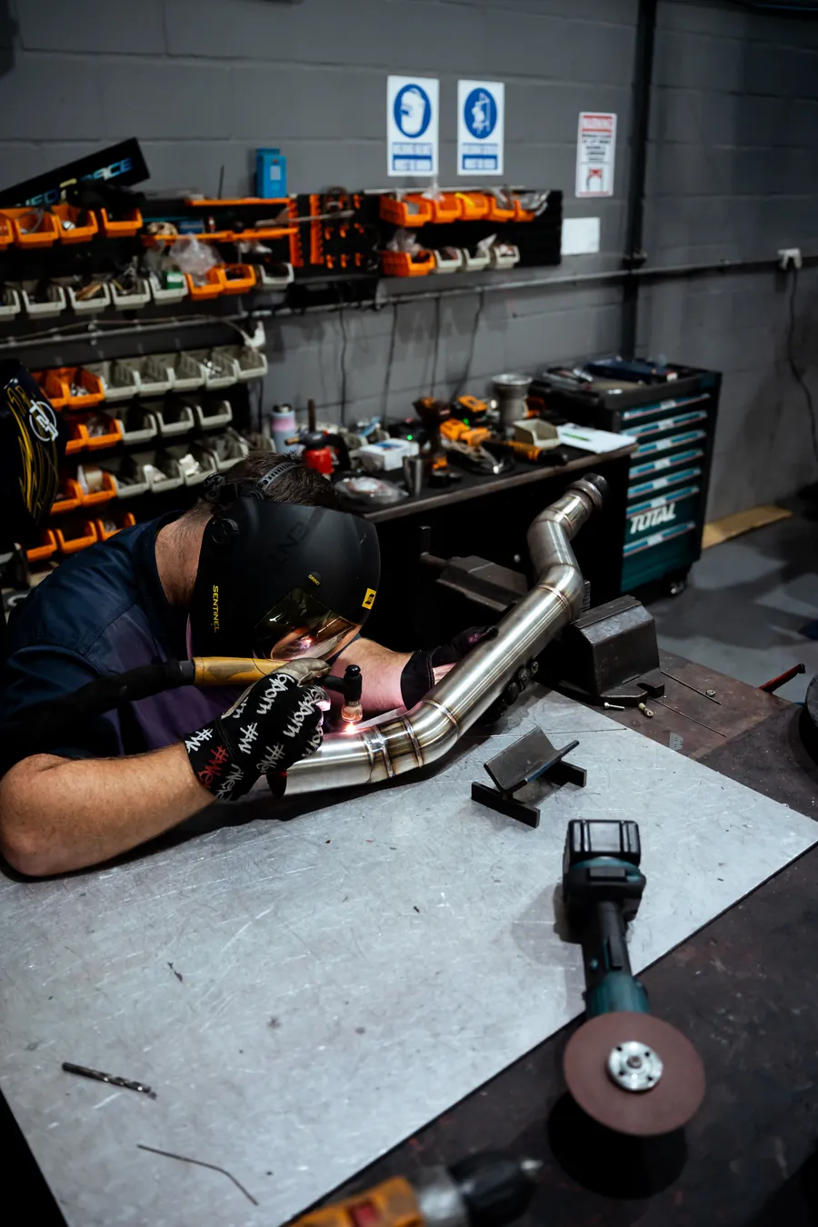 A technician working on exhaust piping at the bench