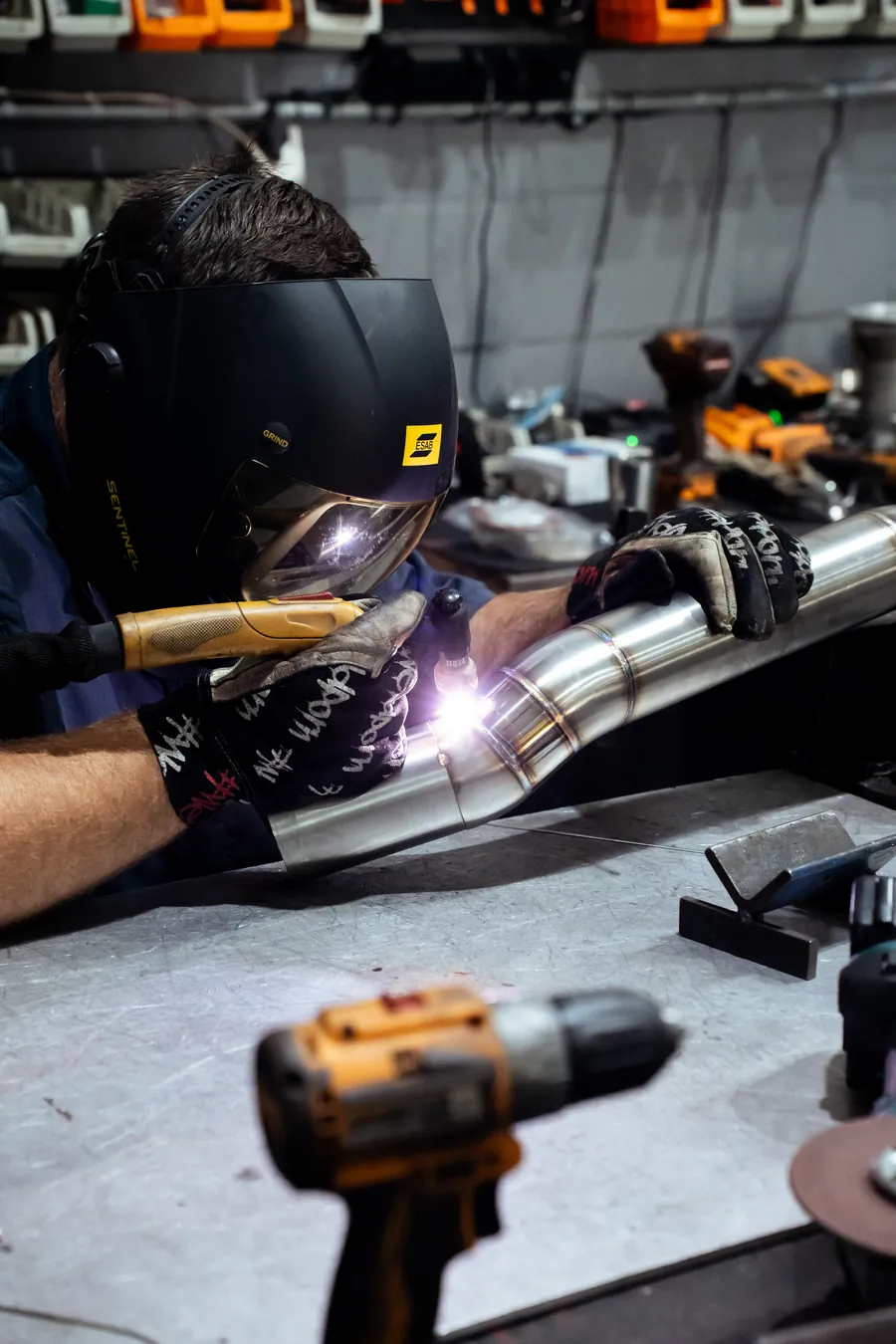 Welding an exhaust section, sparks lighting the bench