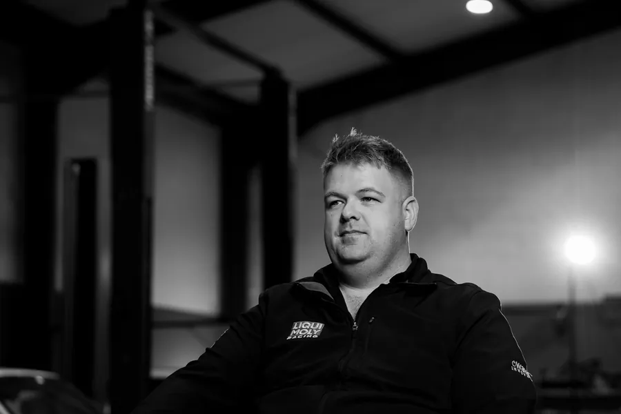 A member of the Tuned 2 Race team seated in the workshop, black and white