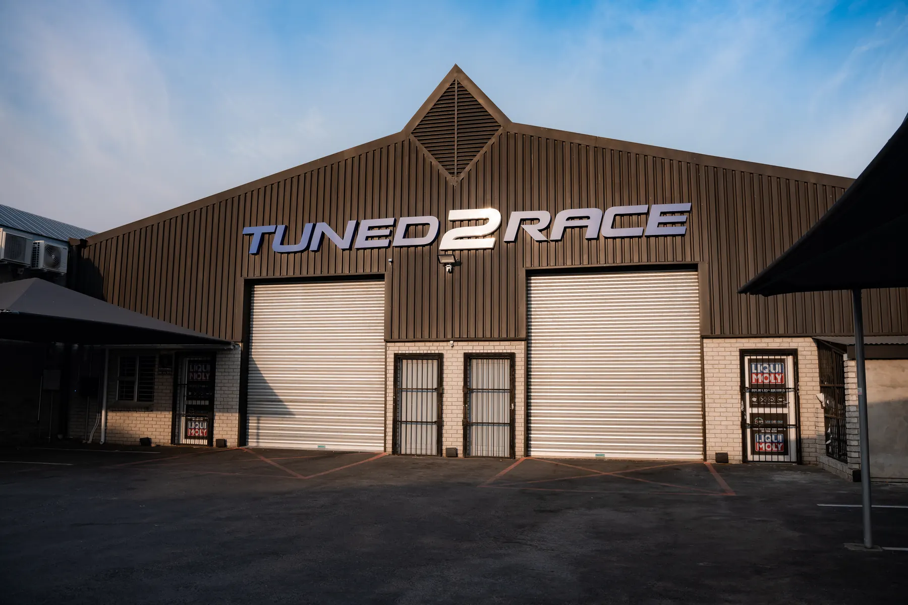 The Tuned 2 Race workshop in Paarl at dusk, roller doors down under the Tuned2Race sign